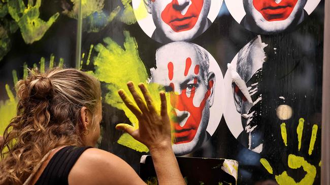 A woman defaces a picture of Prime Minister Benjamin Netanyahu with paint as Israeli anti-government demonstrators stage a protest in Tel Aviv. Picture: AFP