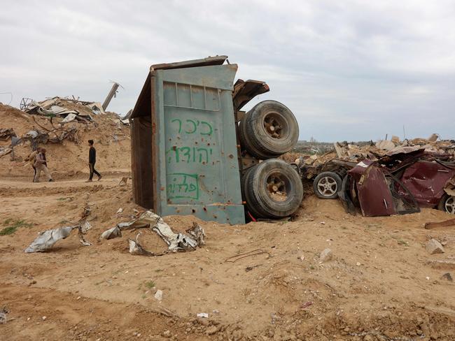 Displaced Palestinians walk past destroyed vehicles as they make their way to the northern parts of the Gaza Strip. Picture: AFP