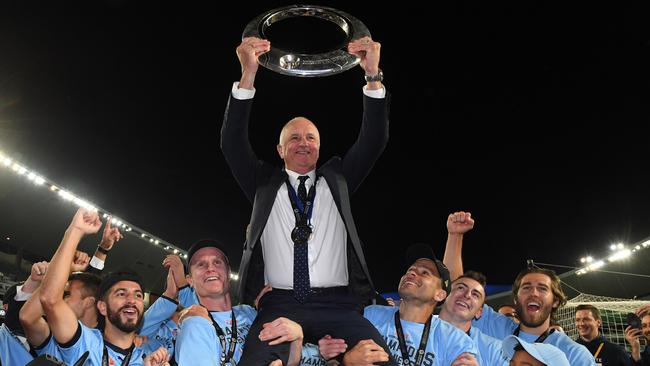 Sydney FC coach Graham Arnold holds up the champions trophy.