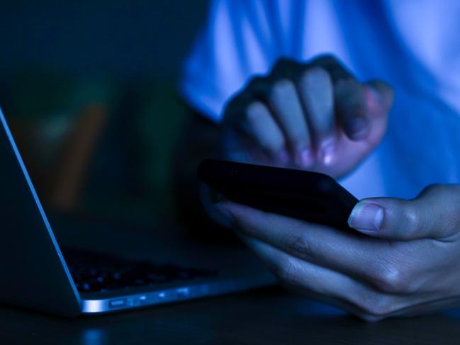 close up young man hand holding smartphone for access by unlock on screen and for register website on internet in the late night at dormitory , internet addiction concept