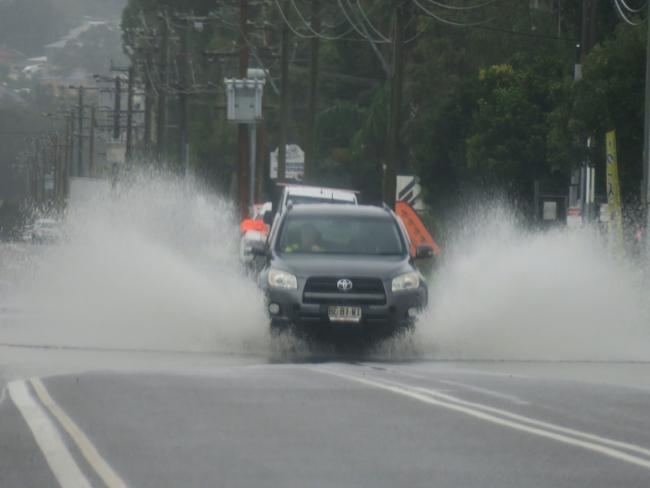 Motorists driving through flood water on Gavenlock Rd, Tuggerah, following torrential rain at the weekend. Picture: Richard Noone