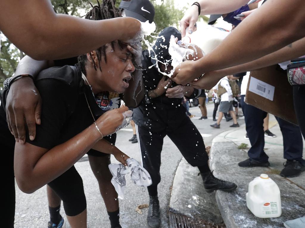 Protesters pour milk in the eyes of a woman affected by teargas during a rally at the Miami Police Department. Picture: Wilfredo Lee/AP