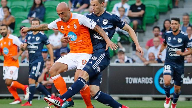 Brisbane Roar’s Massimo Maccarone is challenged by Melbourne Victory defender James Donachie on Friday night.