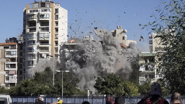 People watch a building collapse after being hit by an Israeli air strike in Ghobeiri, Beirut, Lebanon. Picture: AP.