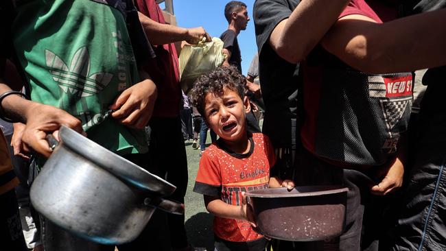 A child cries as Palestinians gather to receive a hot meal at a food distribution point in the Nuseirat camp for refugees in the central Gaza Strip at the weekend. Picture: AFP