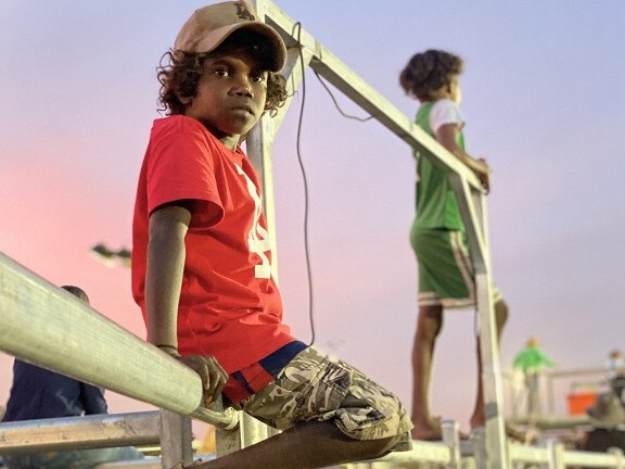 Two boys climb to the top of the fence to get the best view of the rodeo at the Katherine Show. Picture: Supplied.