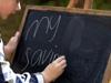 Kid writing on blackboard /File