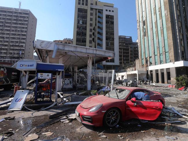 People check the damage to their car as it sits parked in a petrol station near the explosion site. Picture: STR/AFP