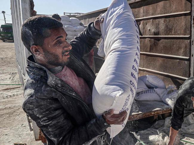 Workers unload bags of humanitarian aid that entered Gaza by truck through the Kerem Shalom (Karm Abu Salem) border crossing in the southern part of the Palestinian territory on February 17, 2024, in Rafah on the southern Gaza Strip, amid the ongoing conflict between Israel and the Palestinian militant group Hamas. (Photo by SAID KHATIB / AFP)