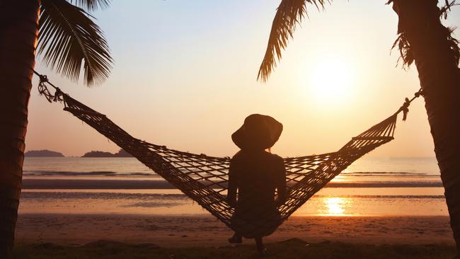 woman relaxing in hammock at sunset on the beach. istock image