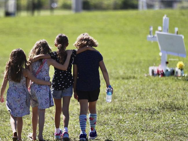 Children approach a vigil post in Parkland, Florida to honour the 17 people who were killed by a former student at Marjory Stoneman Douglas High School. Picture: CM. Guerrero/The Miami Herald/AP