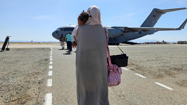 An evacuee holding a sleeping toddler walks toward an Abu Dhabi-bound Emirati plane at Port Sudan airport on May 10. Picture: Mohamad Ali Harissi / AFP