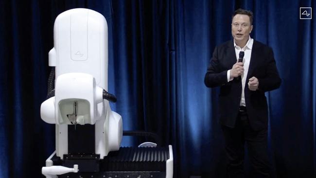 Elon Musk standing next to the surgical robot during his Neuralink presentation.