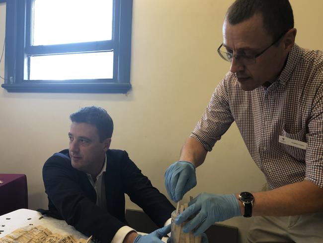 Mayor Michael Regan (left) assists State Library of NSW conservationist Jonathan London remove the contents of the time capsule. Picture: Jim O'Rourke