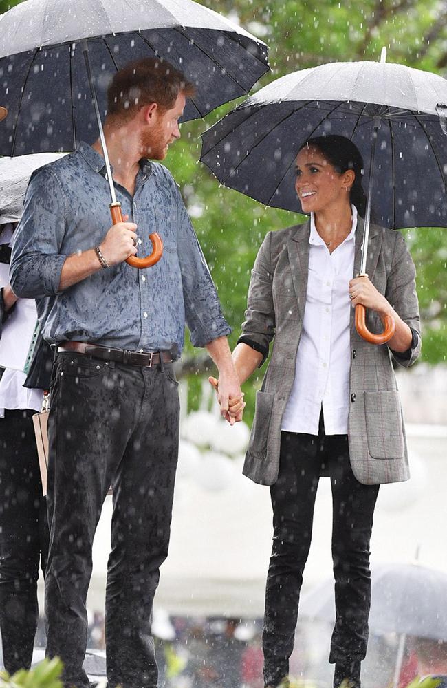 Stop it, guys! Harry and Meghan share another loving moment in the rain. Picture: Tim Rooke/Rex/Shutterstock/Splash