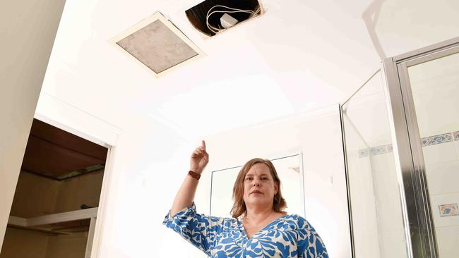 Arana Hills resident Jodie Davis points to a hole in her roof after a tree from a neighbouring property crashed inside her house, which had the roof forced out of her home after a tree from a neighbouring property crashed through the roof, triggering a dispute over who owns the tree. Picture: Patrick Woods.