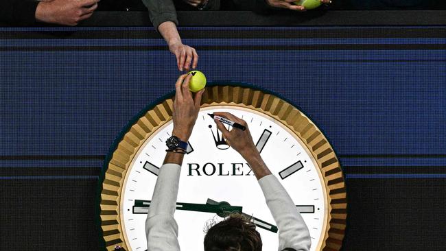 Russia's Daniil Medvedev signs autographs above the clock as he leaves the court after victory against Finland's Emil Ruusuvuori in their men's singles match on day five of the Australian Open tennis tournament in Melbourne early on January 19, 2024. (Photo by Anthony WALLACE / AFP) / -- IMAGE RESTRICTED TO EDITORIAL USE - STRICTLY NO COMMERCIAL USE --