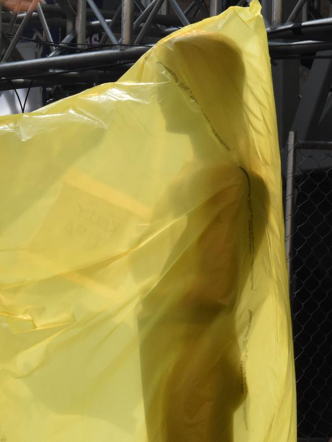 An Oscar statue is covered by plastic on the red carpet.