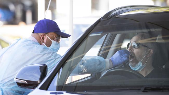 A worker tests a member of the public at a Perth drive through testing site.