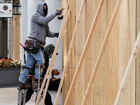 Workers board up shop fronts in Washington. Picture: Reuters.