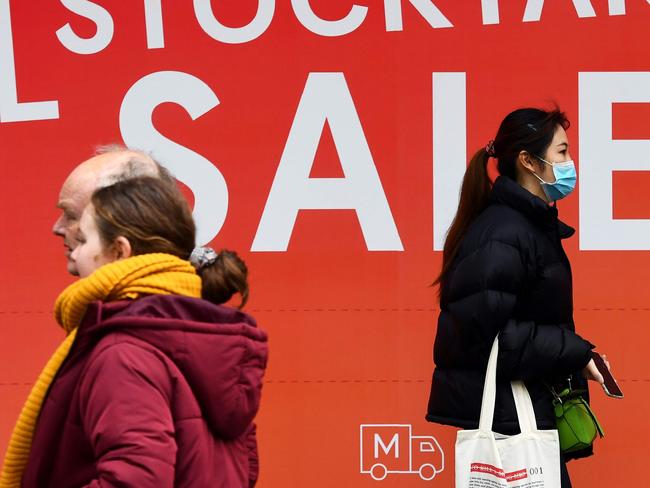 People walk past a sale sign in a department store window in Melbourne's central business district on June 3, 2020. - Australia is heading for its first recession in nearly three decades after the economy shrunk in the January-March quarter, with a "far more severe" reading expected in the next three months as the effects of the virus shutdown bite. (Photo by William WEST / AFP)