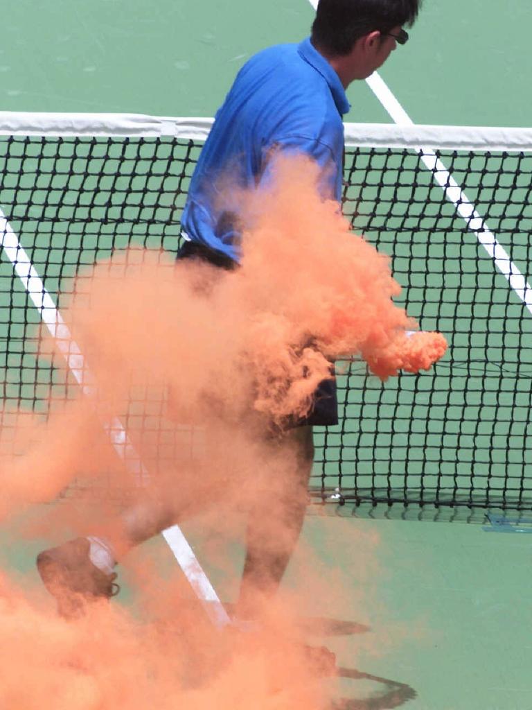 A tennis official cleans up the damage caused by a flare.