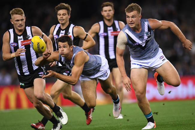 Port Adelaide’s Ryan Burton (left) fires out the handball in front of Ollie Wines (right) and Collingwood’s Adam Treloar (left) in the Round 7 match at Marvel Stadium. Picture: Julian Smith/AAP