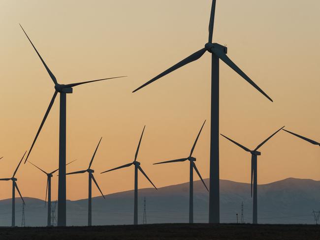 This photograph taken on February 13, 2023 at sunset shows wind turbines in a wind farm in Fuendejalon, with the Moncayo mount in background, Zaragoza province, northern Spain. (Photo by CESAR MANSO / AFP)