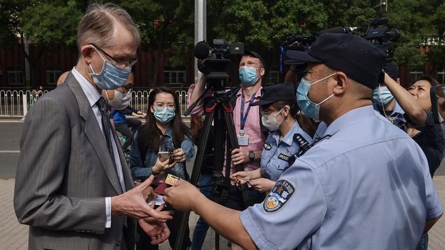 A Chinese police officer returns an ID card to Australian ambassador to China Graham Fletcher, left, as he arrives at the Beijing Second Intermediate People's Court on Thursday. Picture: AFP