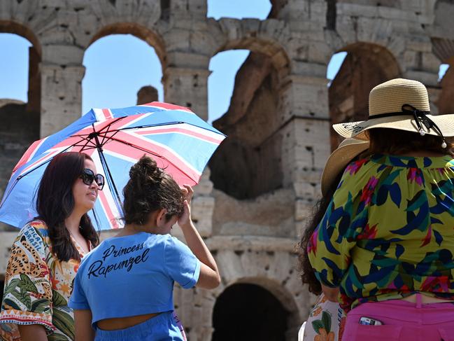 Tourists shelter from the sun with umbrellas near the Colosseum in Rome. Picture: AFP