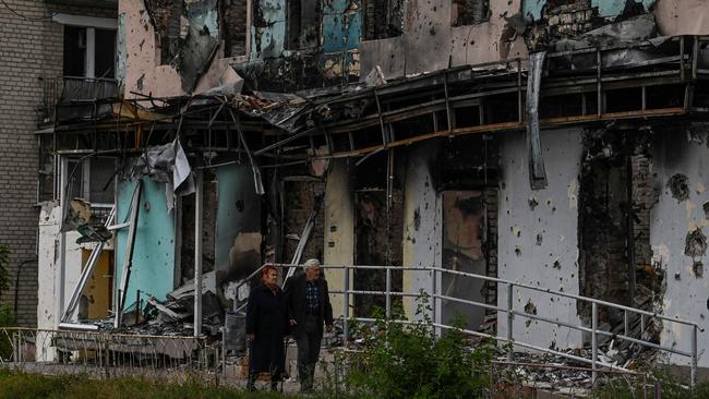 A couple walks between debris in the city of Izium, Kramatorsk, eastern Ukraine,over the weekend. Picture: AFP