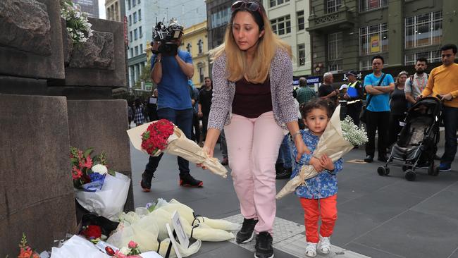 A small child lays flowers with her family member. Picture: Alex Coppel