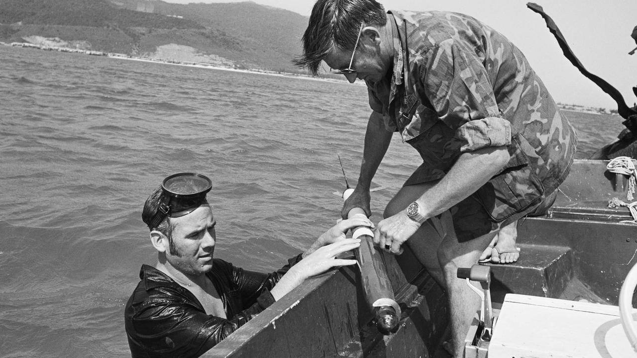 Divers from RAN Clearance Diving Team 3 (CDT3) recovering unexploded ordnance from the water at Da Nang, South Vietnam. The sailor in the water is ABCD Tony Ey and the sailor in the boat receiving the 2.75" rocket is CPOCD John Gilchrist, both of the 8th Contingent CDT3. Pic: The Australian War Memorial