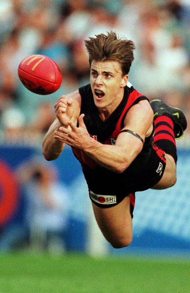 1999: Essendon star Matthew Lloyd just manages a handball in a game against Sydney. Picture: Michael Dodge