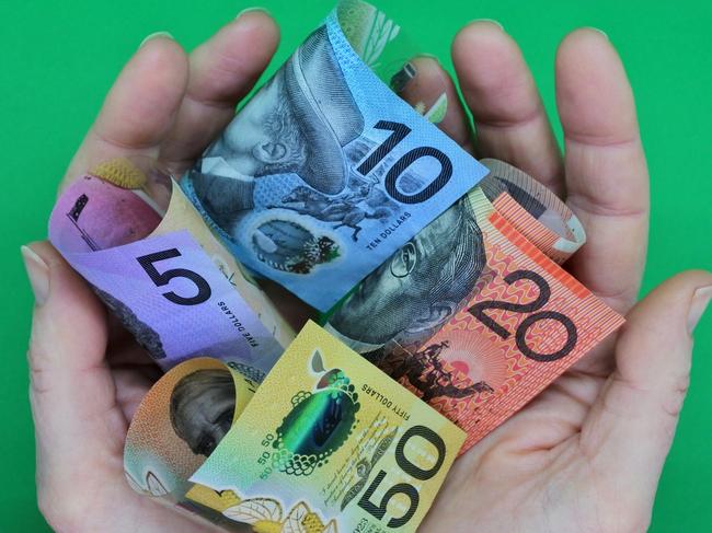 POV (point of view) of a person holding Australian dollar currency bank notes with his two hands isolated on a green background. ; share dividends generic