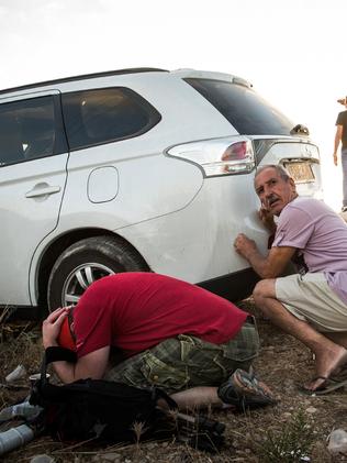 Men take cover behind a car due to a rocket attack siren going off while watching Israeli attacks inside Gaza. Picture: Andrew Burton