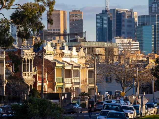 Winter afternoon in Fitzroy at Edinburgh Gardens with Victorian two story heritage houses against Melbourne high-rise CBD skyline, cars parked along suburban street with jogger runner. Picture: Jason Edwards