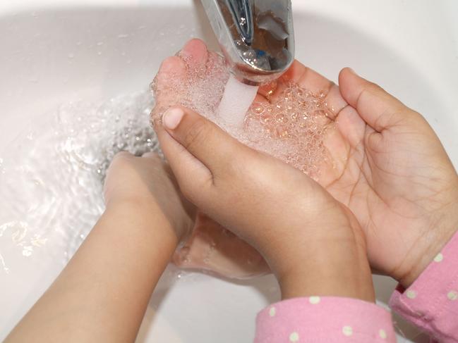 Washing hands under running tap water.