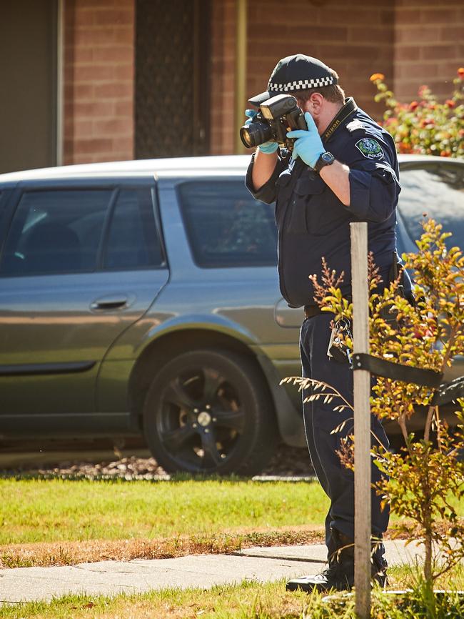 A crime-scene officer photographs evidence, including rocks and garden posts. Picture: AAP / Matt Loxton