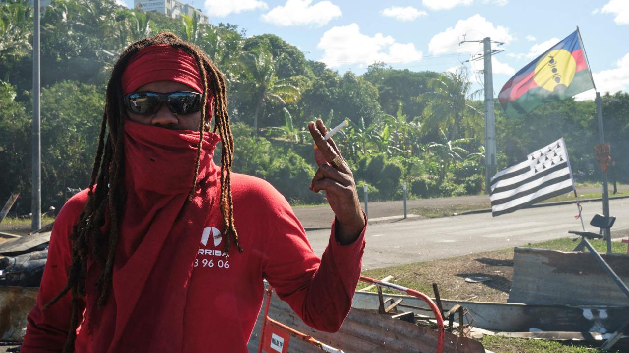 A man stands at a roadblock barricade, with Kanak and Breton flags, controlling access to a district in Noumea, France's Pacific territory of New Caledonia, on May 24. Picture: Theo Rouby / AFP