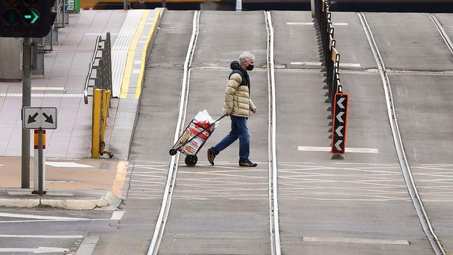 A person crosses an empty street in Melbourne over the weekend. Picture: AFP