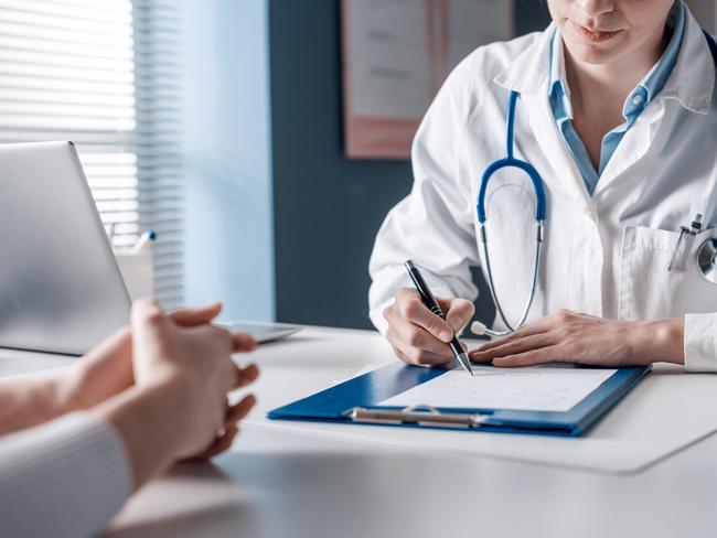 Doctor sitting at desk and writing a prescription for her patient