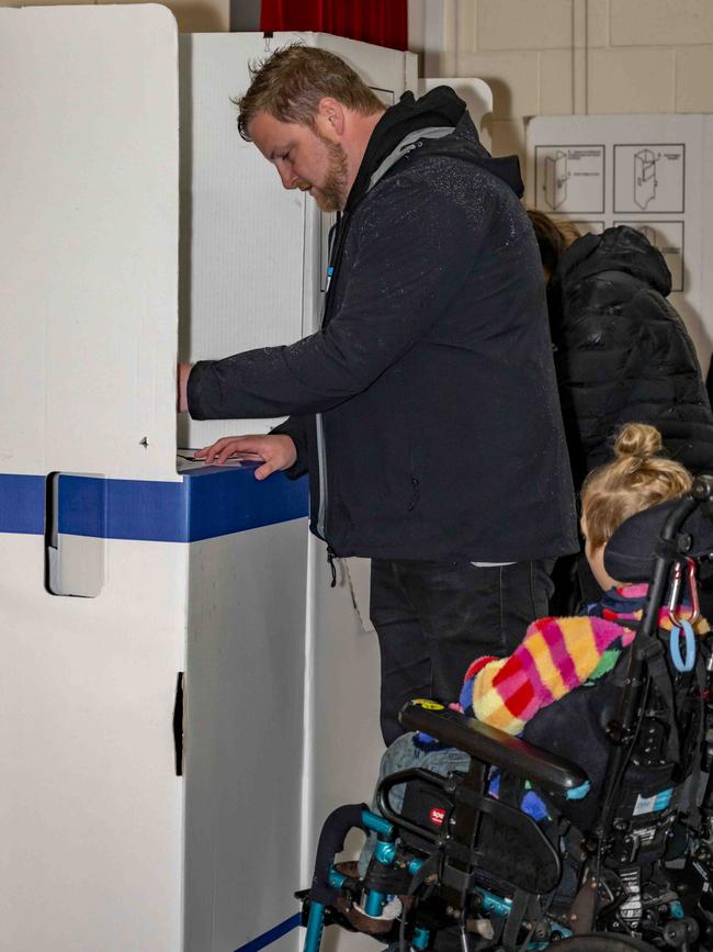 Luke Edmunds accompanied by his family voting at Bellerive Primary School. Picture: Caroline Tan