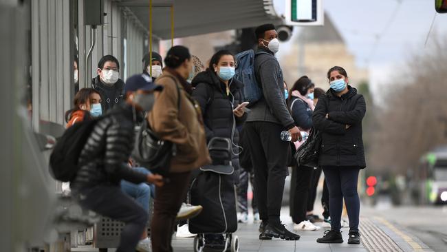 People wait for a tram at Melbourne's Flinders Street Station. Picture: William West/AFP.