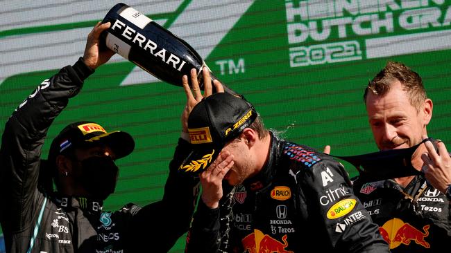 ZANDVOORT, NETHERLANDS - SEPTEMBER 05: Race winner Max Verstappen of Netherlands and Red Bull Racing and second placed Lewis Hamilton of Great Britain and Mercedes GP celebrate on the podium during the F1 Grand Prix of The Netherlands at Circuit Zandvoort on September 05, 2021 in Zandvoort, Netherlands. (Photo by Francisco Seco - Pool/Getty Images)