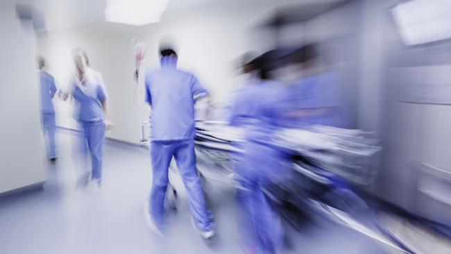 Doctors and nurses pulling hospital trolley,