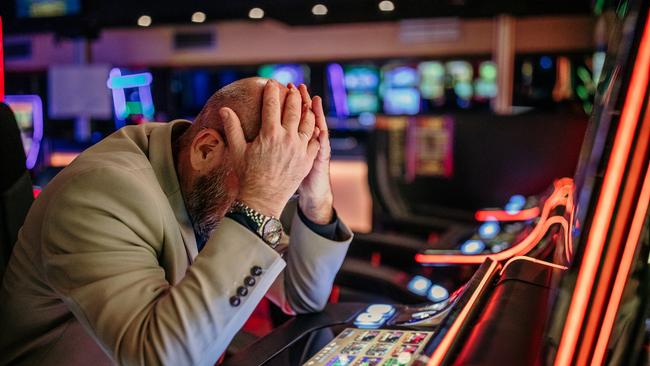 Senior men using slot machine to gamble in night club, having difficulties to make money, he is losing