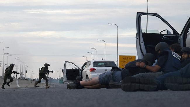 Journalists take cover behind cars as Israeli soldiers take position during clashes with Palestinian fighters near the Gevim Kibbutz, close to the border with Gaza. Picture: AFP