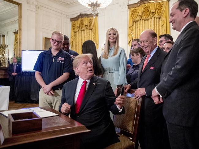 President Donald Trump, accompanied by Ivanka Trump, the daughter of President Donald Trump, center, Commerce Secretary Wilbur Ross, third from right, and Labor Secretary Alex Acosta, second from right, and workers, hands out pens after signing an Executive Order that establishes a National Council for the American Worker during a ceremony in the East Room of the White House, Thursday, July 19, 2018, in Washington. (AP Photo/Andrew Harnik)