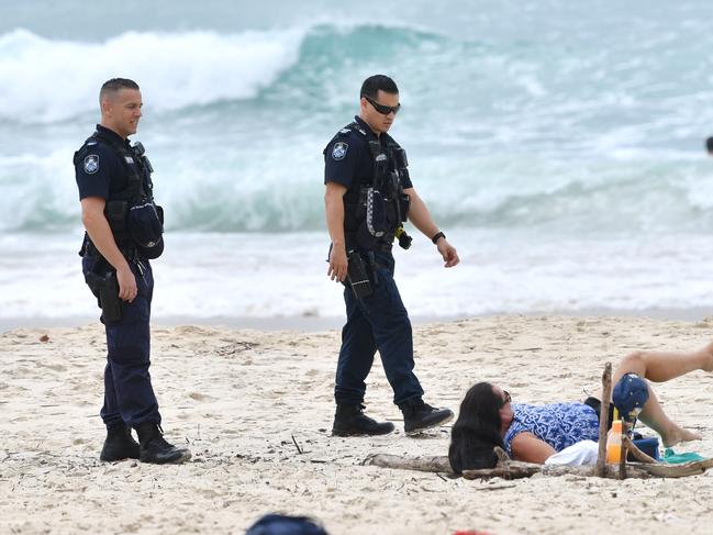 Queensland Police are seen moving on a sunbather at a Gold Coast beach. Photo: Darren England